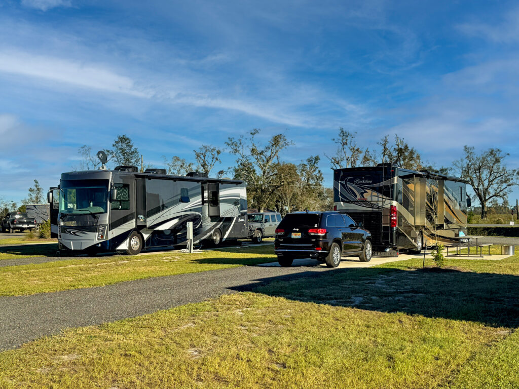 View of Class A RV, level RV site with full hookups and picnic table at The Station RV Resort in Madison, FL