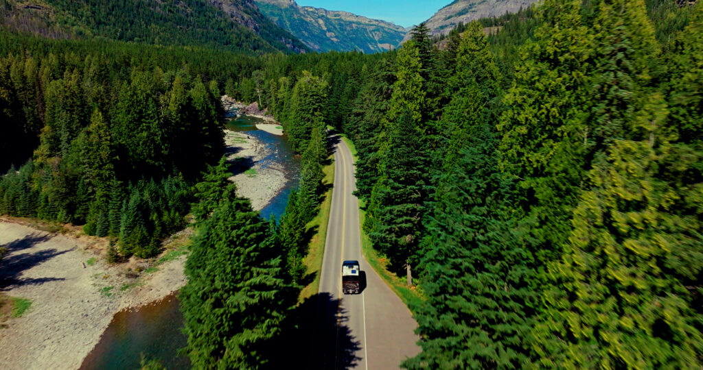 An RV cruising through the beautiful, forested roads of Western Montana on a road trip.