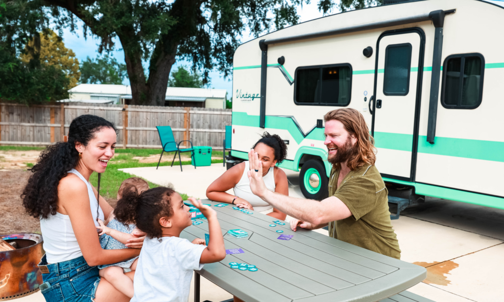 Family enjoying a summer staycation at The Station RV Resort in Madison, Florida while playing a game at a picnic table outside their RV campsite.