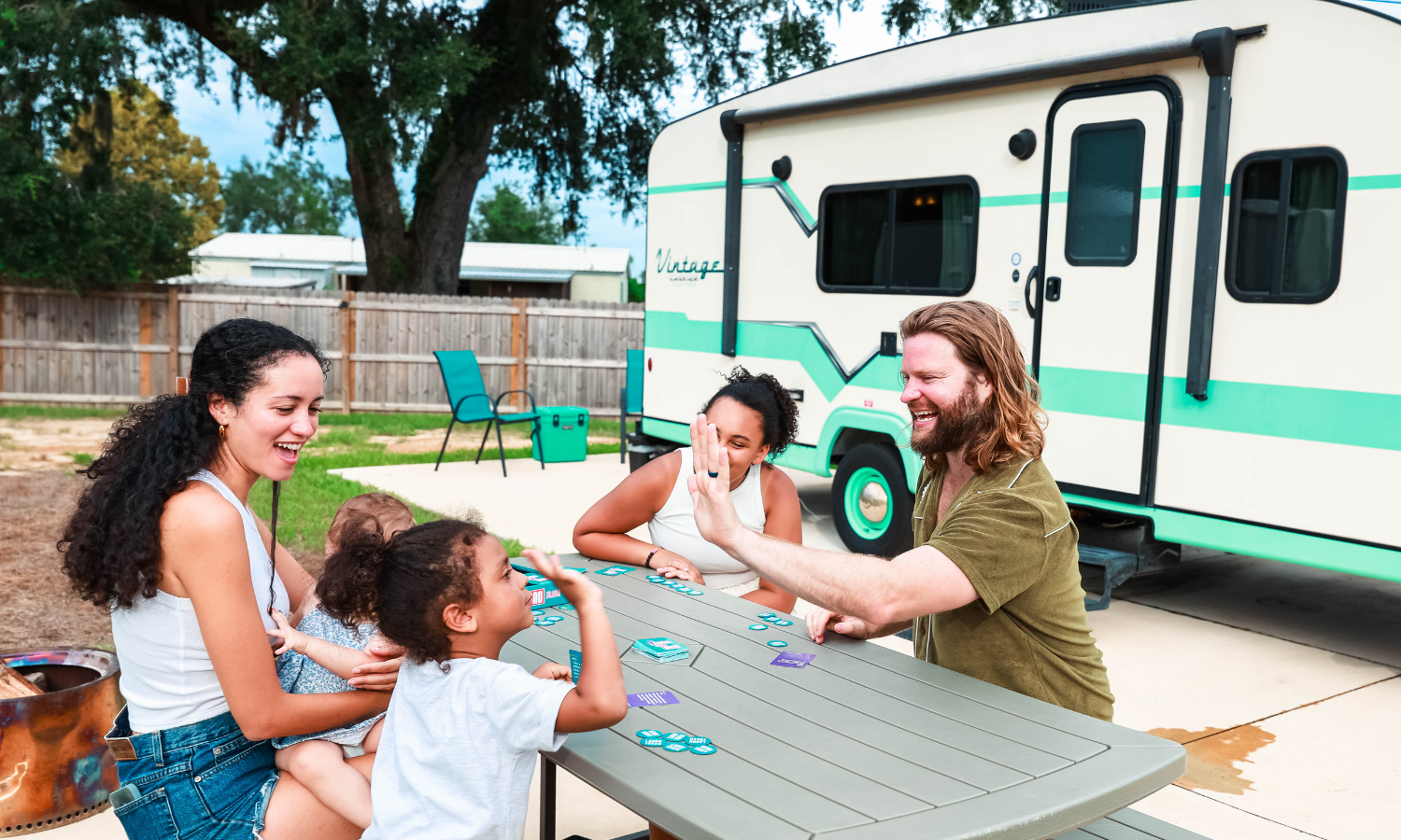 Family enjoying a summer staycation at The Station RV Resort in Madison, Florida while playing a game at a picnic table outside their RV campsite.