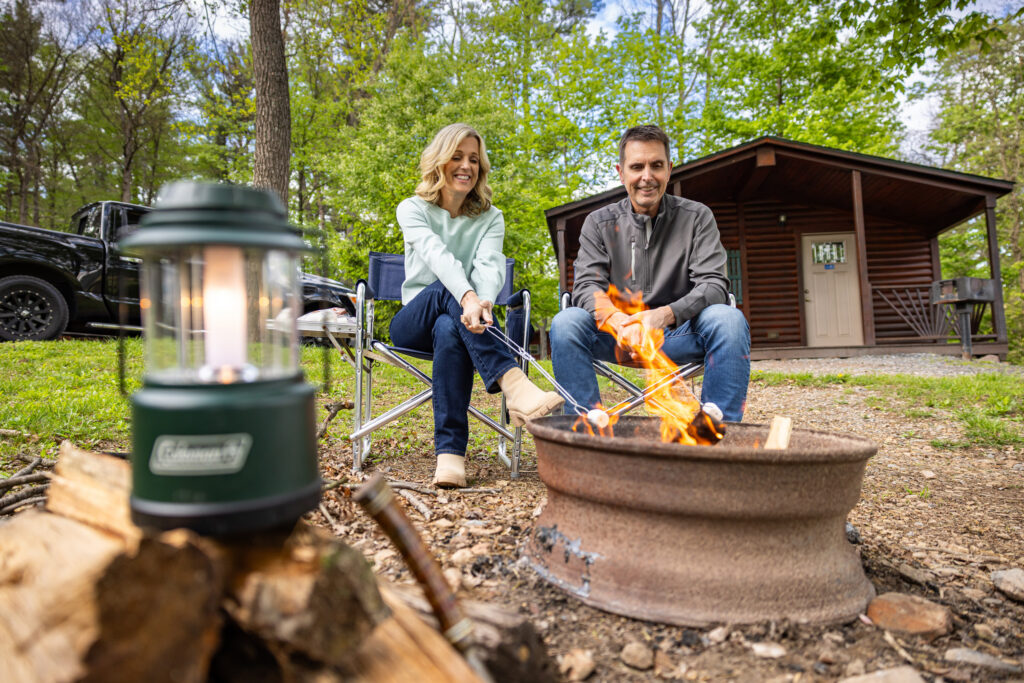 Couple enjoying time around a fire in the outdoors at Twin Grove RV Resort over Labor Day Weekend.