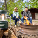 Couple enjoying time around a fire in the outdoors at Twin Grove RV Resort over Labor Day Weekend.