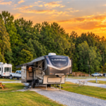 Fifth-wheel RV parked at Rivertown Rose Campground in Vicksburg, Mississippi, beneath a golden sunset, surrounded by spacious campsites and trees.