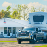 GMC truck towing a fifth-wheel RV in front of The Station RV Resort in Madison, Florida, a convenient stop for snowbird travelers along I-10 and I-75.